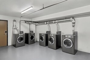 A laundry facility with four washing machines, a ventilation system, and a door. - Red Roof Inn Perryville (Perryville)