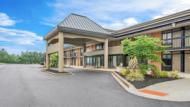 A modern building with a covered entrance, large windows, and a landscaped area with plants. - Red Roof Inn Perryville (Perryville)