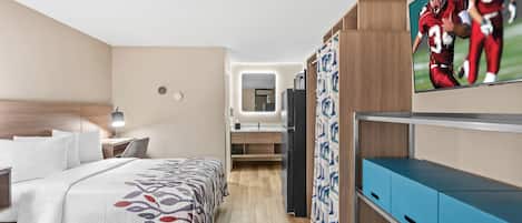 A hotel room with a bed, bedside table, lamp, TV, wardrobe, and a mirror.