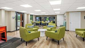 A modern lounge area with green armchairs, a white coffee table, and a vending machine. - Red Roof Inn Perryville (Perryville)