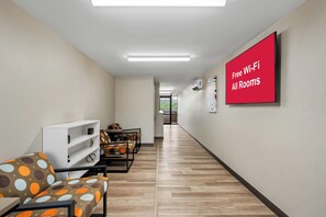 A hotel lobby with a long corridor, seating area with patterned sofas, and a sign indicating free Wi-Fi in all rooms. - Red Roof Inn Perryville (Perryville)
