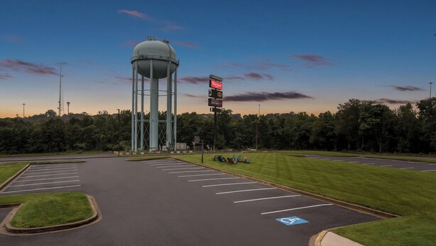 A parking lot with marked handicapped spaces, a water tower, and a signboard. - Red Roof Inn Perryville (Perryville)