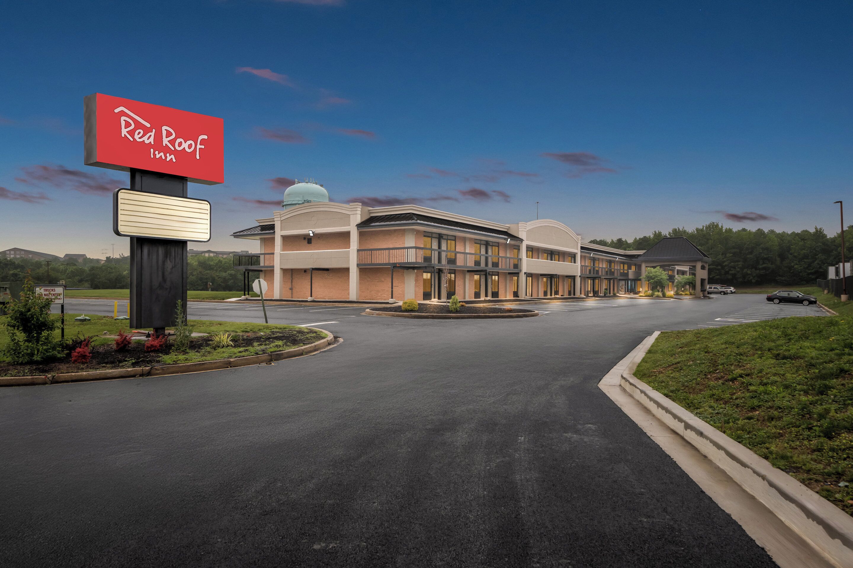 A Red Roof Inn with a modern building, a parking lot, and a landscaped area.
