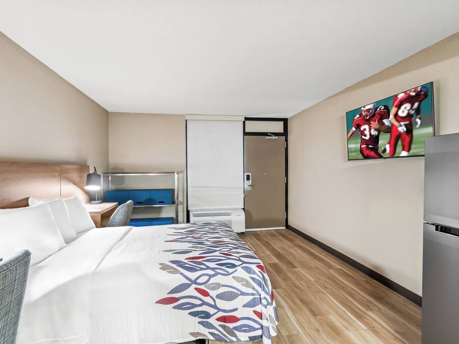Ein Hotelzimmer mit einem Bett, einem Schreibtisch, einem Sessel, einem Fernseher und einem Kühlschrank.