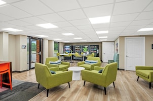 A modern lounge area with green armchairs, a white coffee table, and a vending machine.