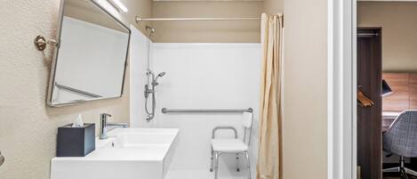 A small bathroom with a sink, mirror, and shower.