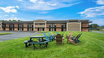 A building with a parking lot and outdoor seating area with tables and chairs.