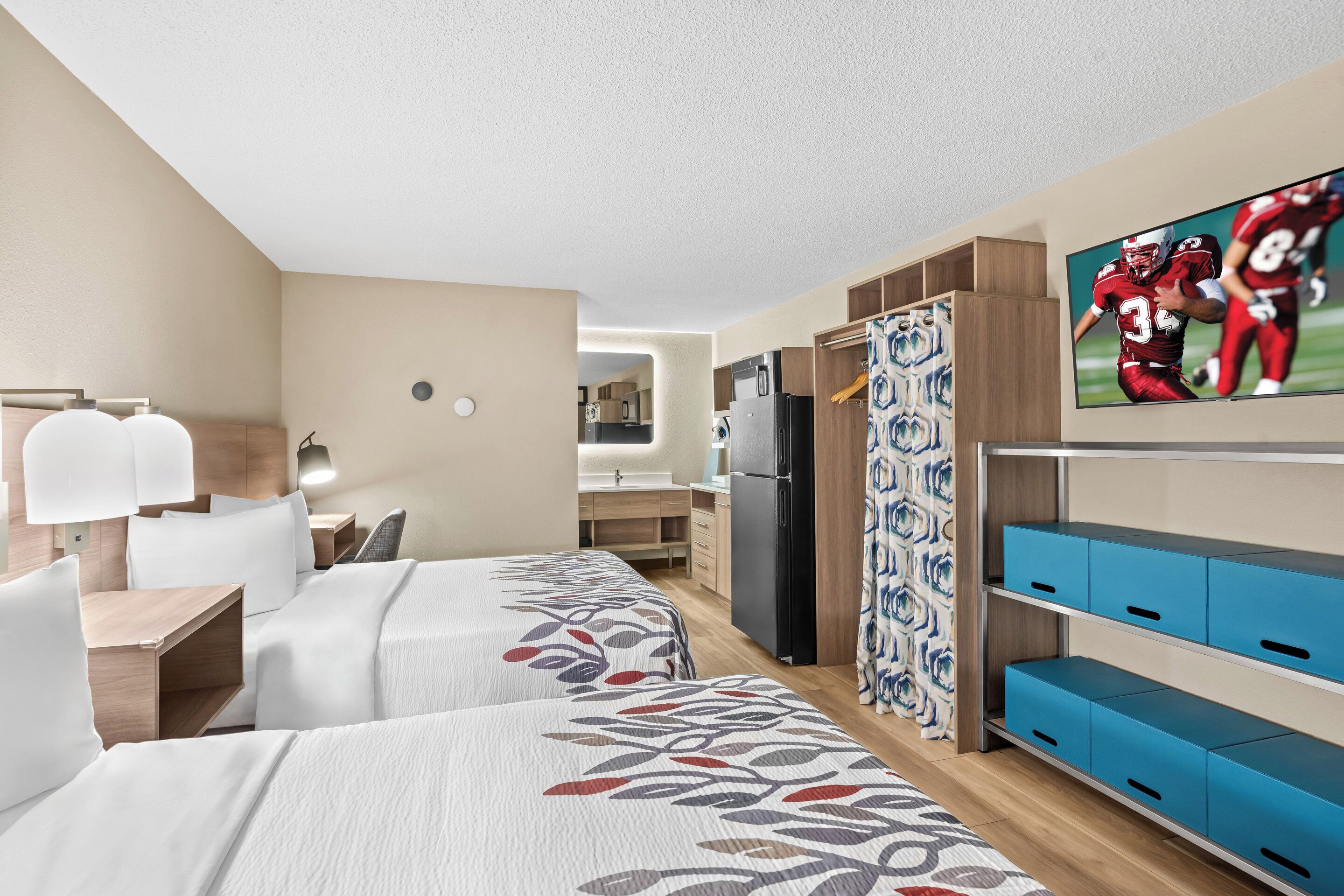 Une chambre d’hôtel avec deux lits, une télévision, un bureau et une armoire.