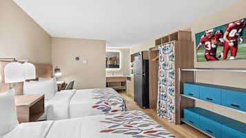Une chambre d’hôtel avec deux lits, une télévision, un bureau et une armoire.