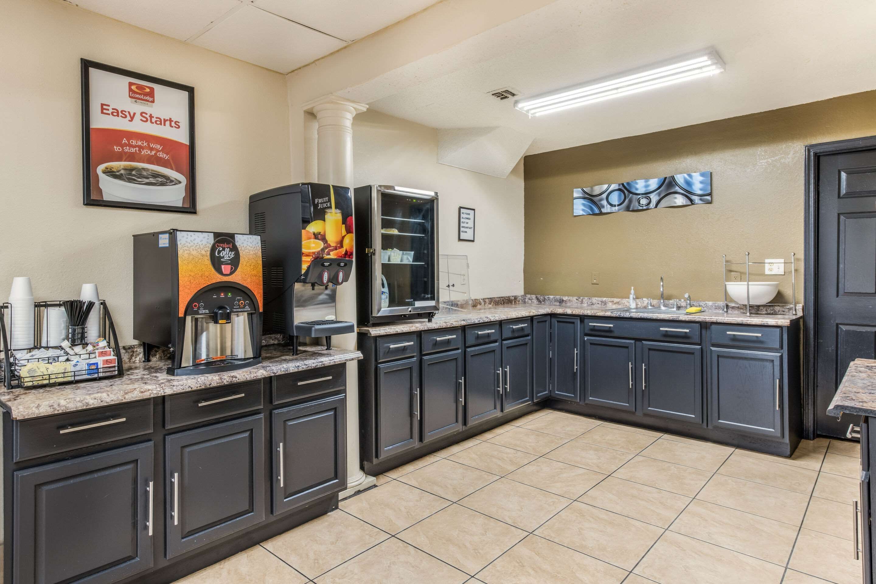 Una cocina moderna con armarios oscuros, una estación de café y un refrigerador para frutas.