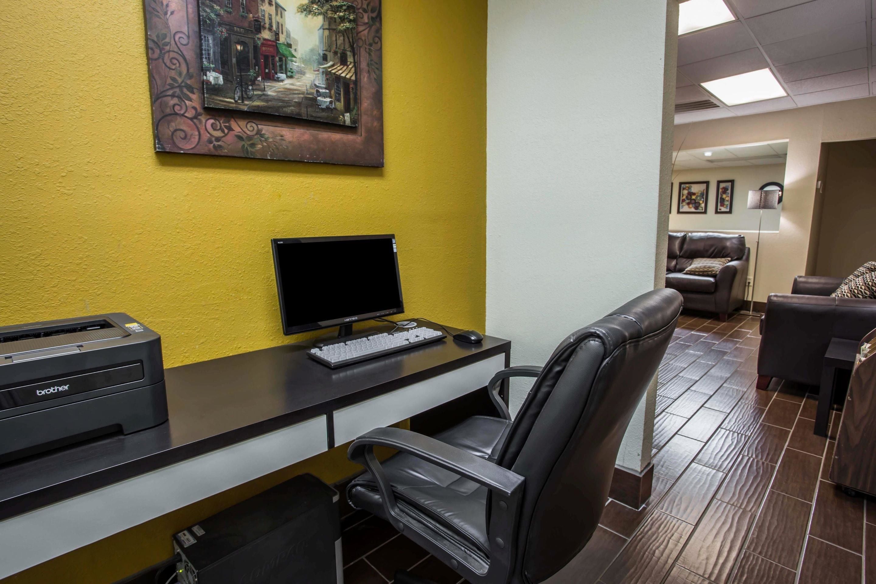 Un espacio de oficina moderno con escritorio, computadora, impresora y sillón de cuero.