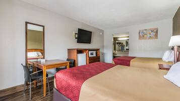 Habitación de hotel con dos camas, un escritorio, una silla, un televisor y un microondas.