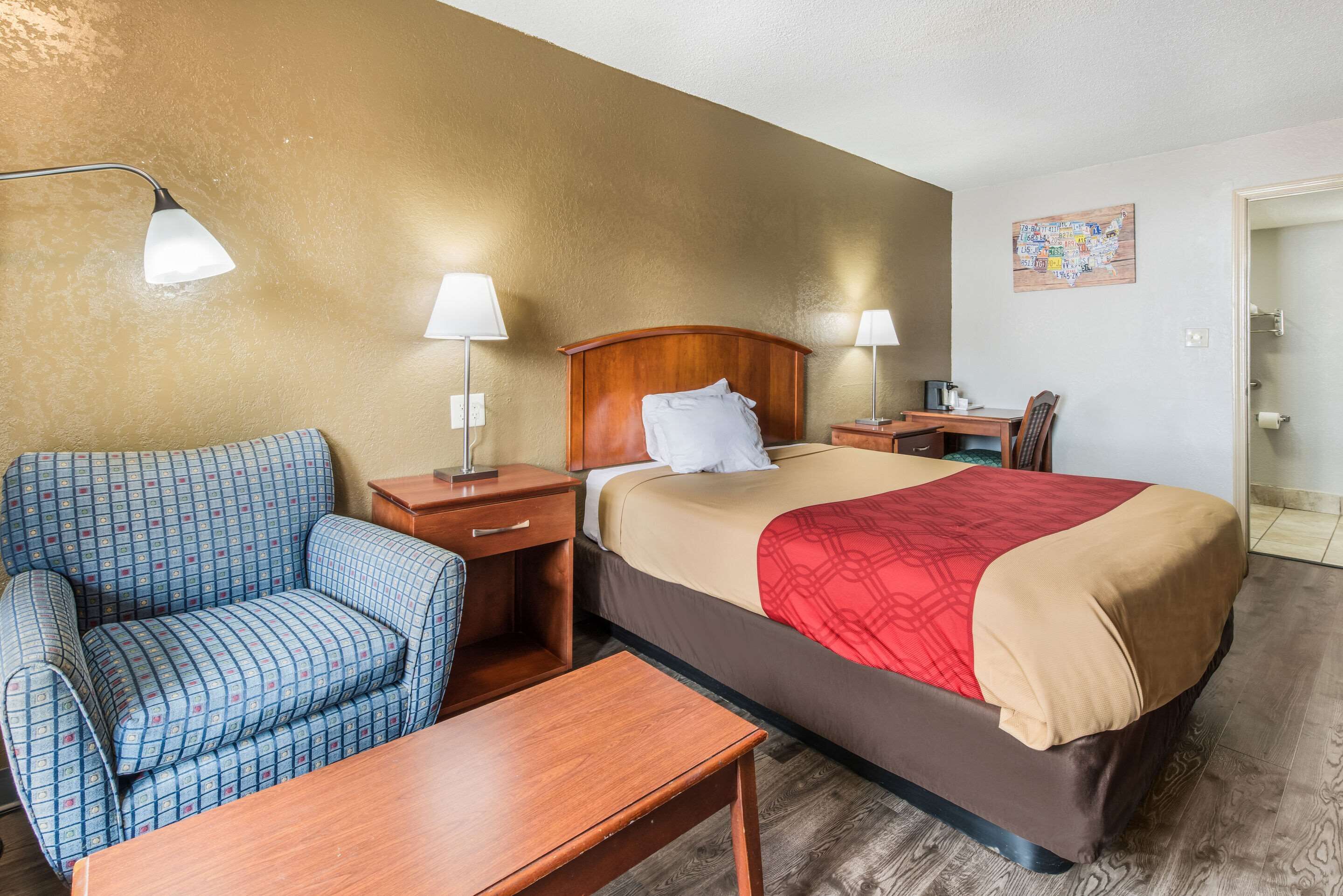 A hotel room with a bed, a sofa, a desk, and two lamps.