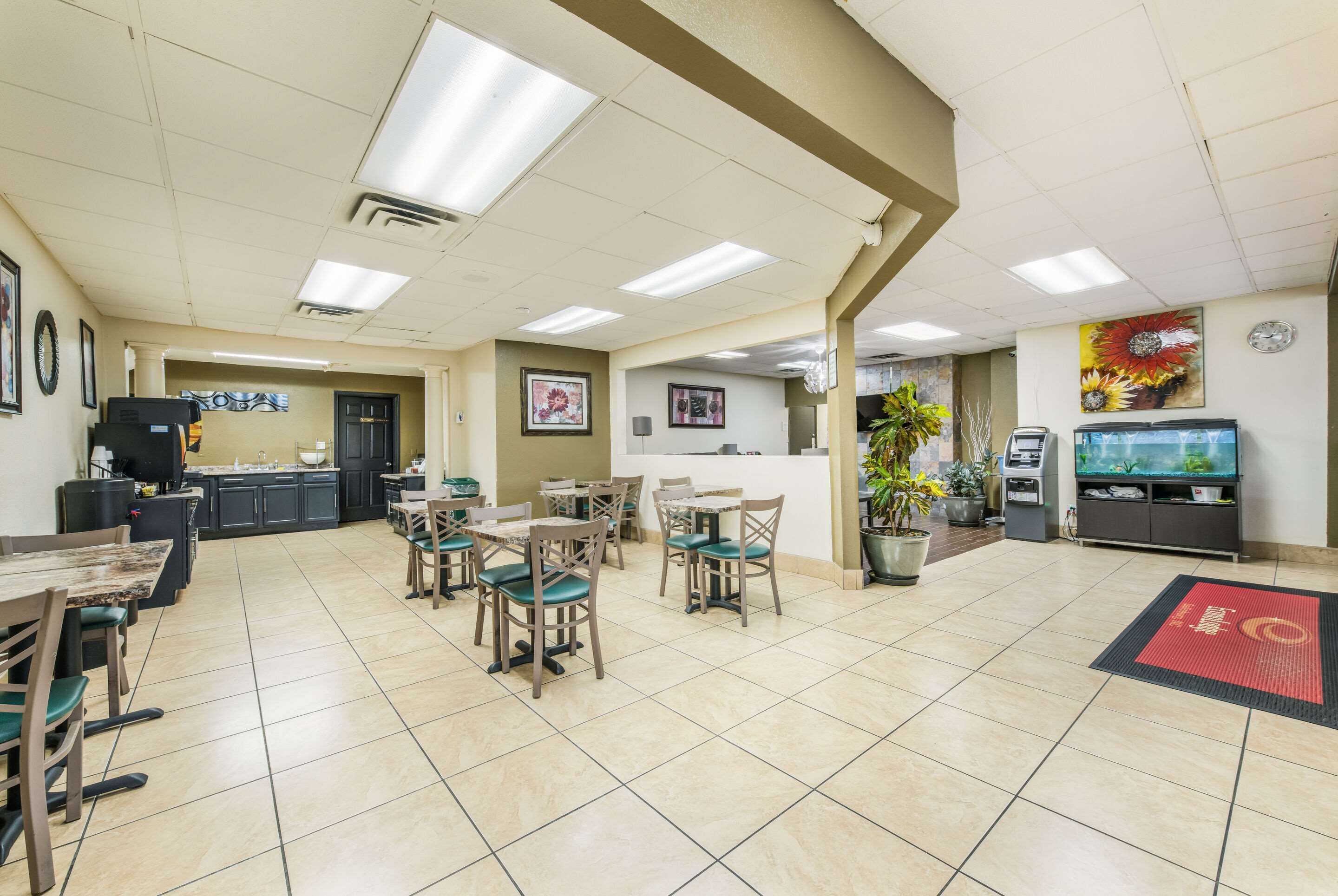 A spacious dining area with multiple tables and chairs, a kitchen area with cabinets and appliances, and a reception desk with a counter.