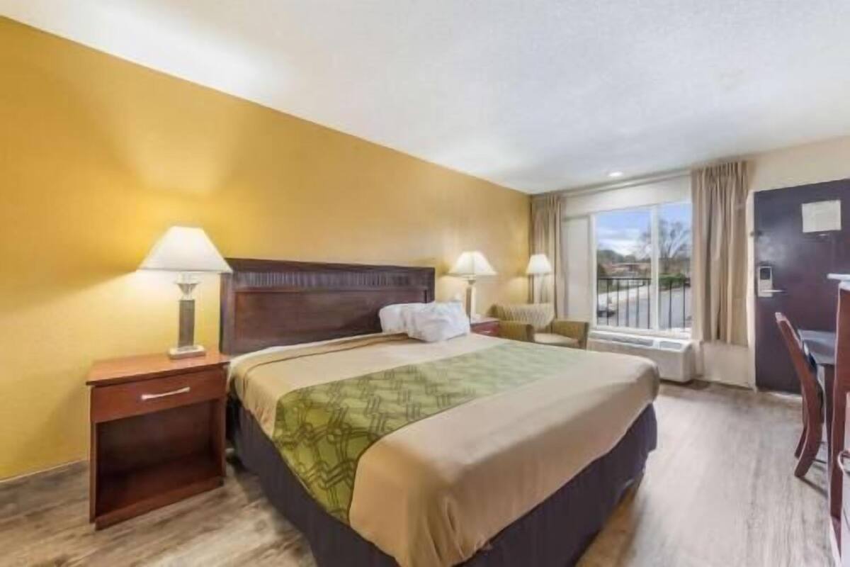 A hotel room with a large bed, two bedside tables, a desk, and a window with a view.