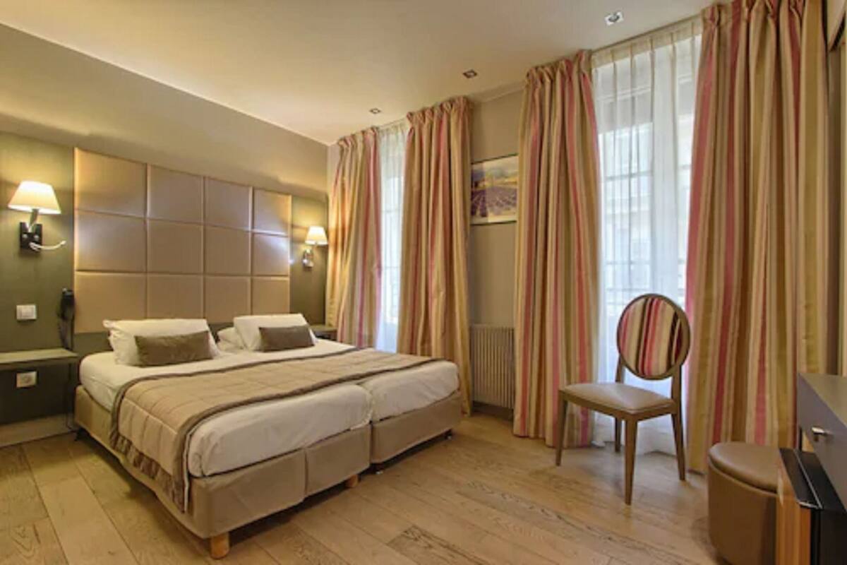 A hotel room with a double bed, two bedside tables, a chair, and a desk.