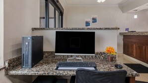A home office setup with a desktop computer, keyboard, mouse, and a monitor on a granite countertop. - MainStay Suites Joliet I-80 (Joliet)