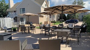 An outdoor patio area with wicker furniture, tables, and umbrellas. - Residence Inn by Marriott Denver Tech Center (Greenwood Village)