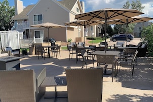 An outdoor patio area with wicker furniture, tables, and umbrellas.