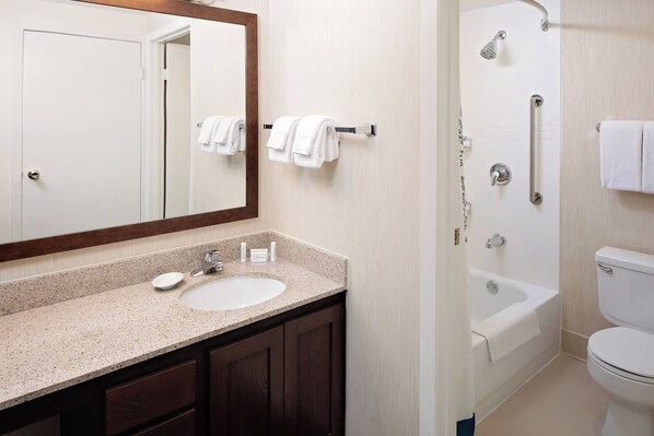 A bathroom with a sink, mirror, towel rack, shower, and toilet.
