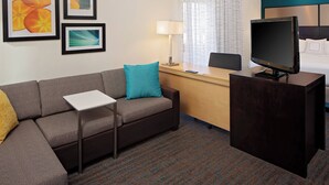 A hotel room with a sofa, a desk, a television, and framed artwork on the wall. - Residence Inn by Marriott Denver Tech Center (Greenwood Village)
