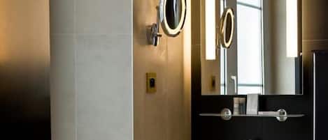 A modern bathroom with a white sink, a large mirror, and a towel hanging on a rack.