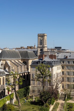A historic building with a clock tower, surrounded by lush greenery and a clear blue sky. - Hôtel Observatoire Luxembourg (Paris)