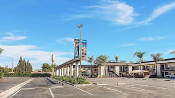 A hotel with a parking lot, a large banner, and a clear blue sky.