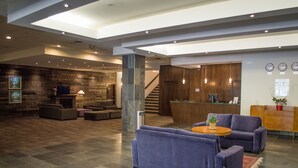 Un vestíbulo amplio con mostrador de recepción, sofás y una escalera que conduce a los pisos superiores.