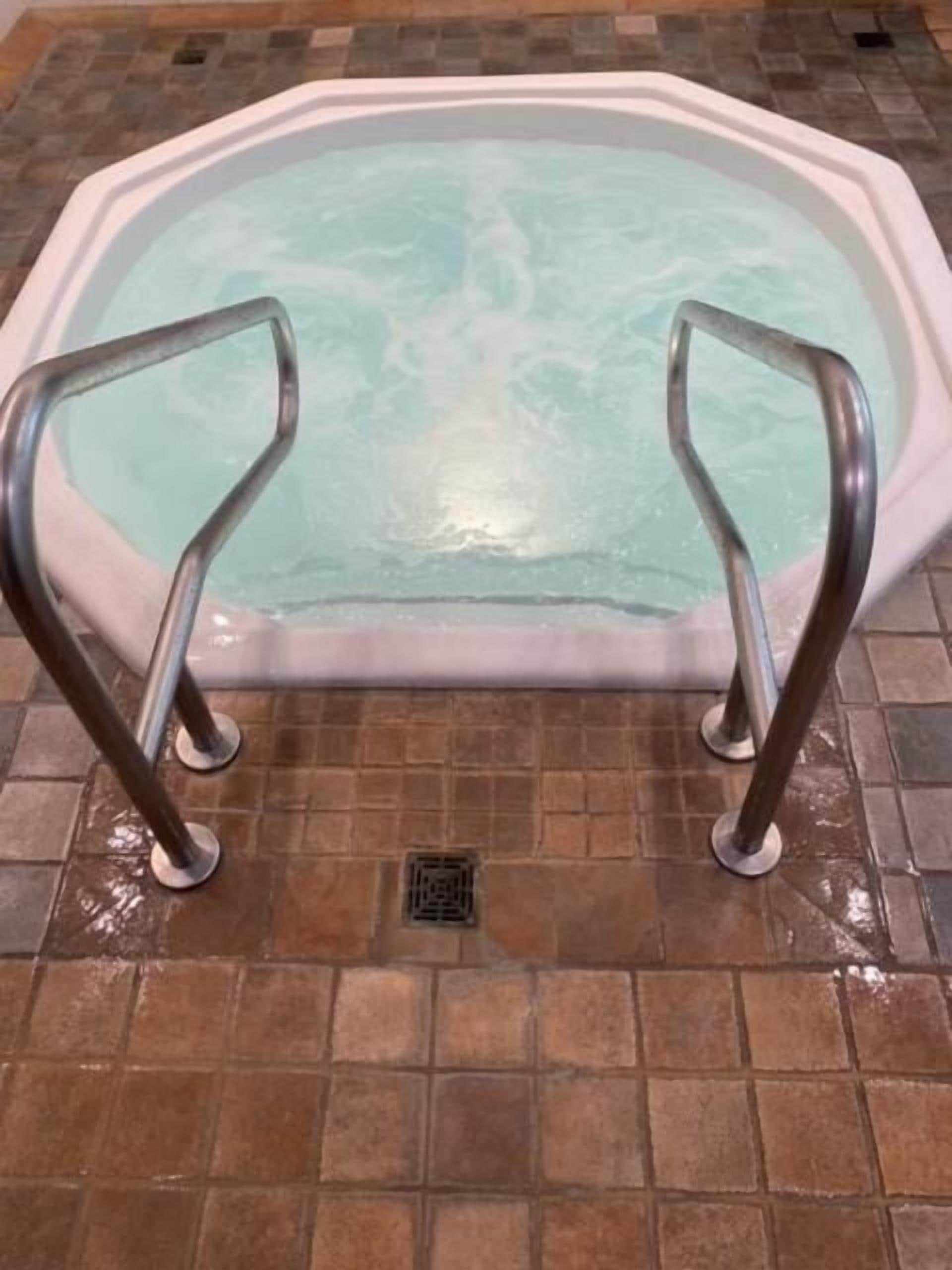 Un jacuzzi con barandillas de metal y suelo de baldosas.