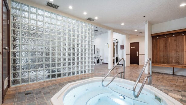 Un área de spa con jacuzzi, suelo de baldosas y una pared divisoria de vidrio.