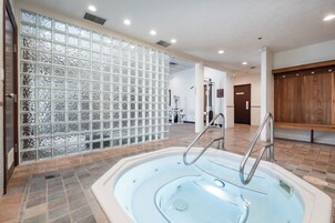 Un área de spa con jacuzzi, suelo de baldosas y una pared divisoria de vidrio.
