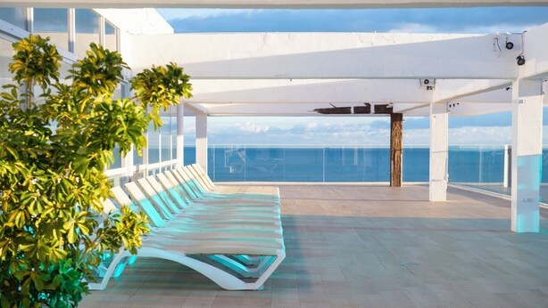A rooftop lounge with a row of sun loungers, a potted plant, and a view of the sea. - Leonardo Hotel Torremolinos Costa del Sol (Torremolinos)