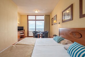 A hotel room with a bed, a desk, a chair, a TV, and a window with a view.