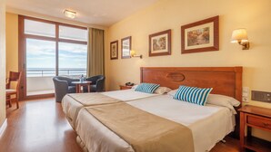 A hotel room with two beds, a desk, a chair, a window with a view, and wall-mounted artwork. - Leonardo Hotel Torremolinos Costa del Sol (Torremolinos)