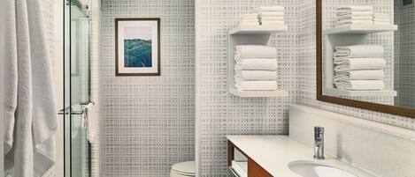 Ein Badezimmer mit Dusche, Toilette, Waschbecken und Handtuchhaltern.