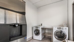 A laundry room with a stainless steel refrigerator, two white LG washing machines, and a small shelf. - Best Western Kent Narrows Inn (Grasonville)