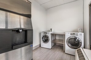 A laundry room with a stainless steel refrigerator, two white LG washing machines, and a small shelf. - Best Western Kent Narrows Inn (Grasonville)