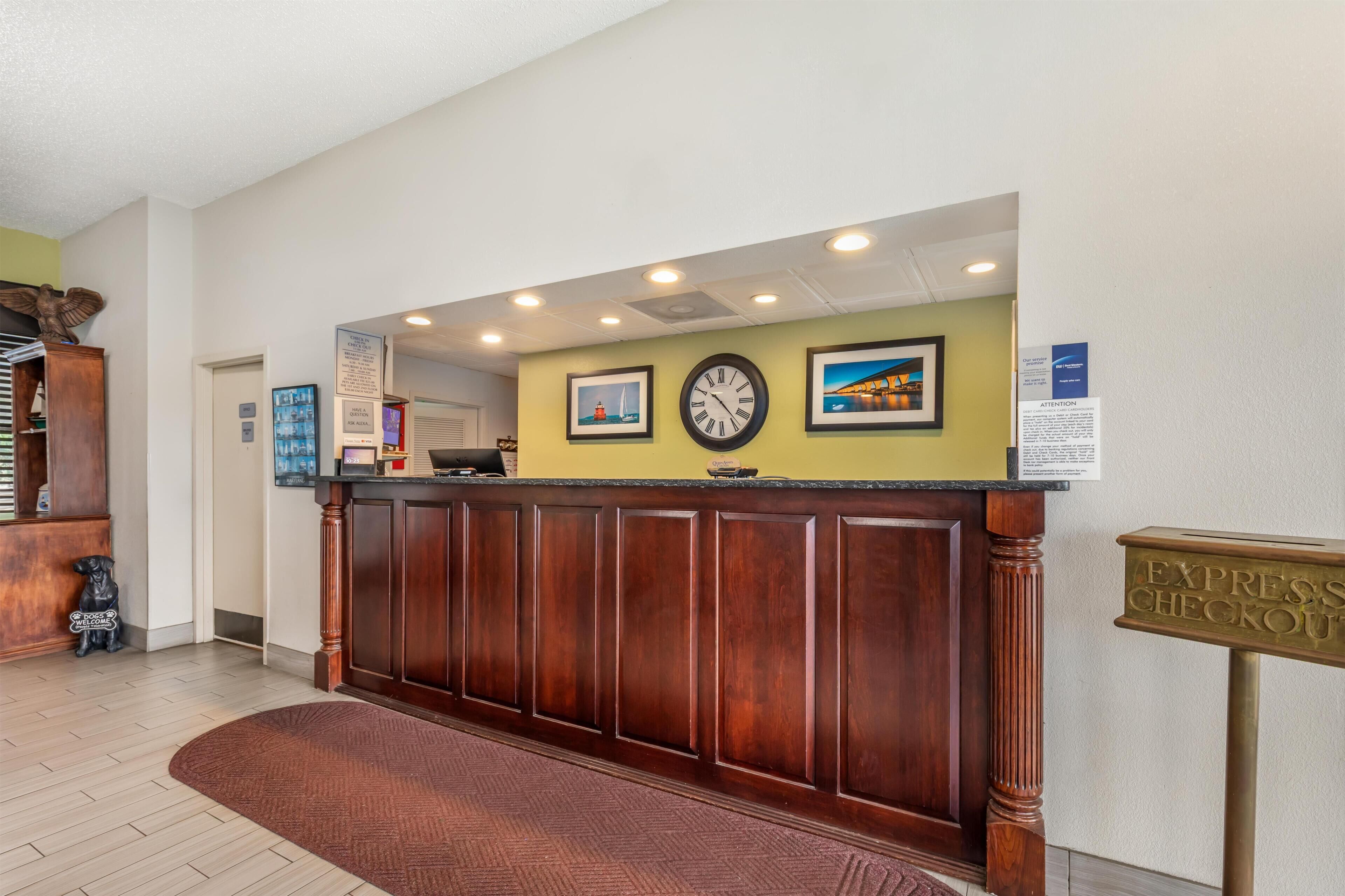 A reception desk with a clock, framed pictures, and a sign for express checkout.