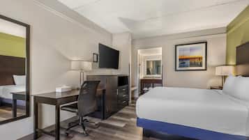 Ein Hotelzimmer mit Bett, Schreibtisch, Stuhl, Fernseher und einem Gemälde an der Wand.