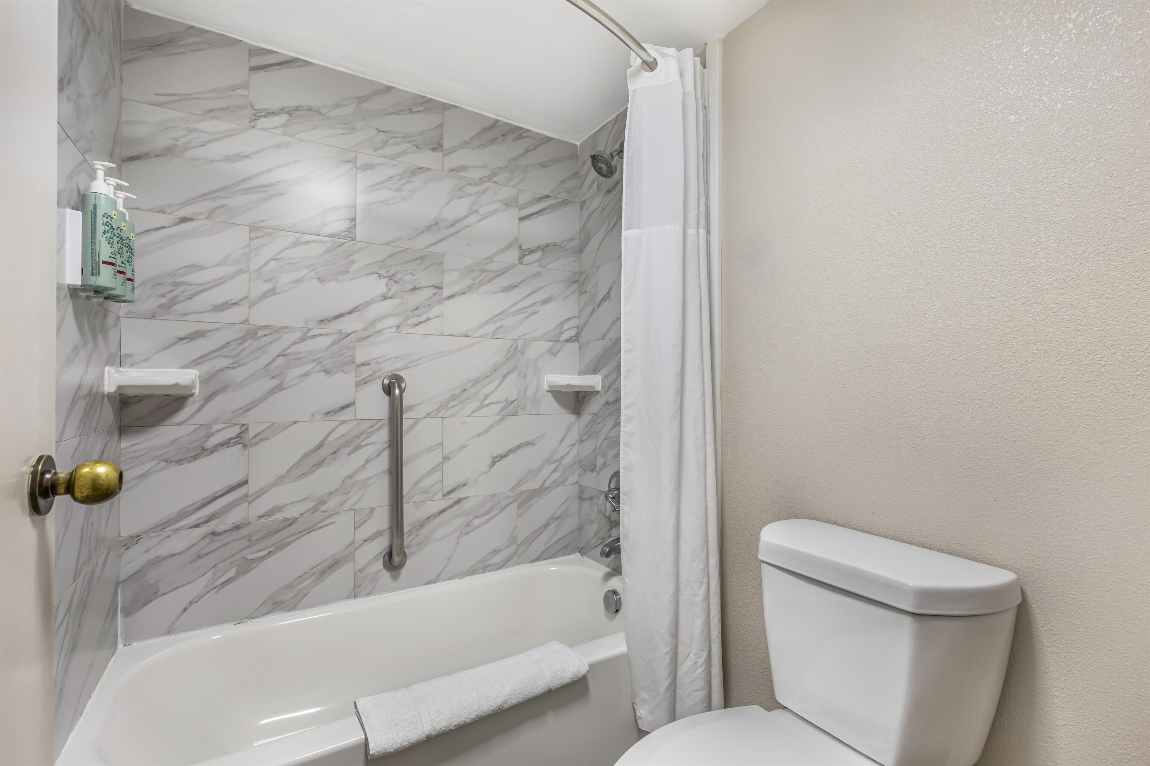 A bathroom with a bathtub, toilet, and a shower area.