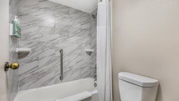 A bathroom with a bathtub, toilet, and a shower area.