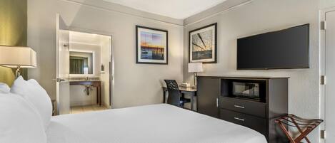 Una habitación de hotel con una cama, un escritorio, un televisor de pantalla plana y obras de arte en las paredes.