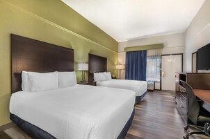 Une chambre d’hôtel avec deux lits, un bureau, une chaise et un téléviseur.