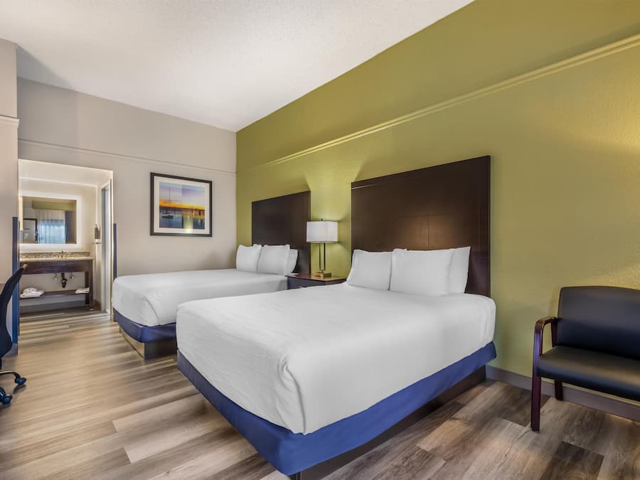 Een hotelkamer met twee bedden, een bureau, een stoel en een badkamer.