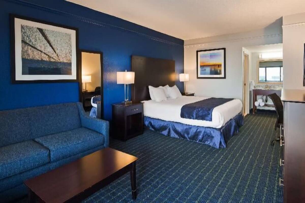 A hotel room with a bed, a sofa, a desk, and two lamps.