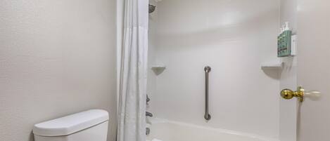 Un baño con inodoro, bañera y cortina de ducha.