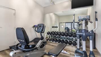 A gym with exercise equipment, a bench, and a wall-mounted mirror.