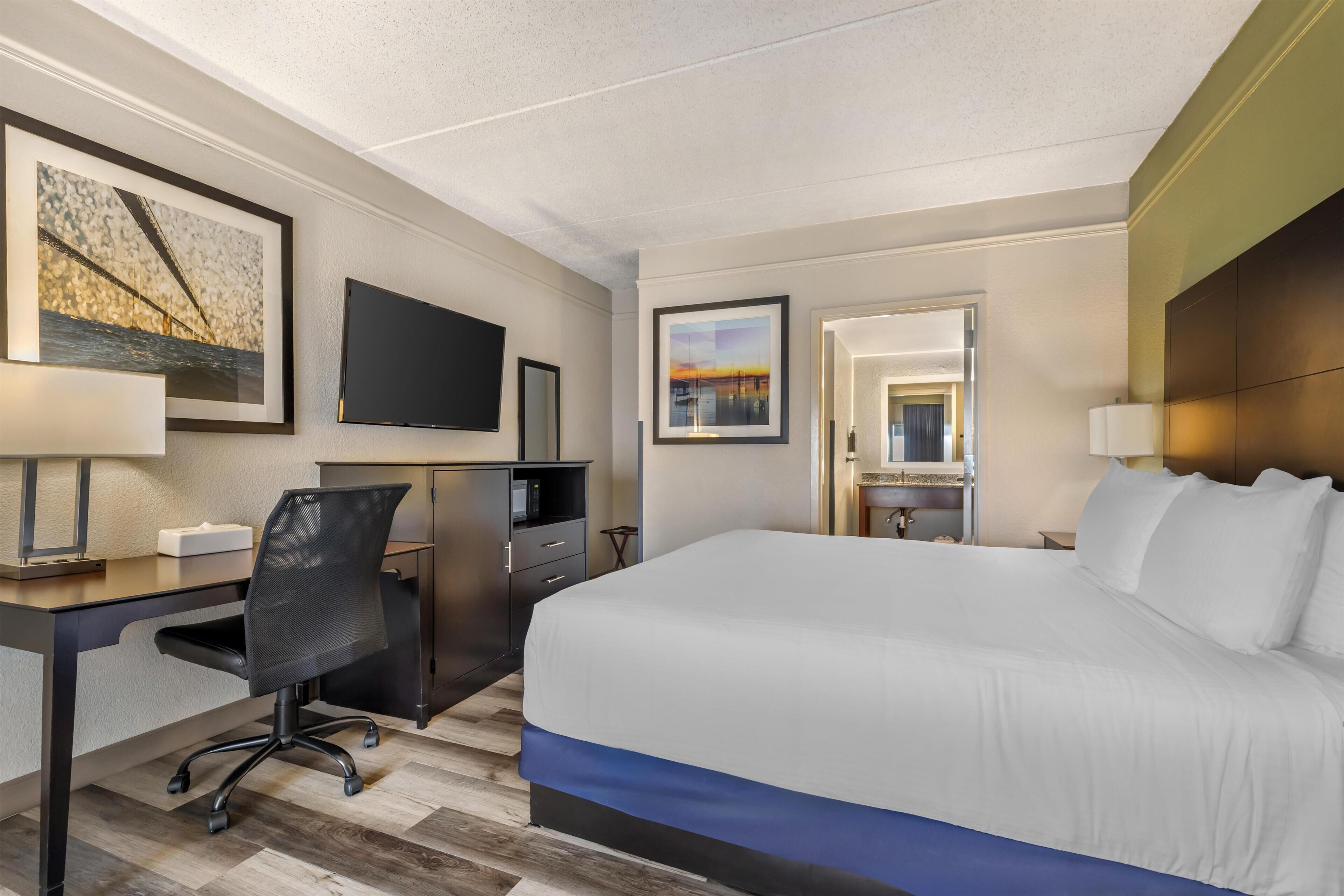 Una habitación de hotel con cama, escritorio, silla y televisor.