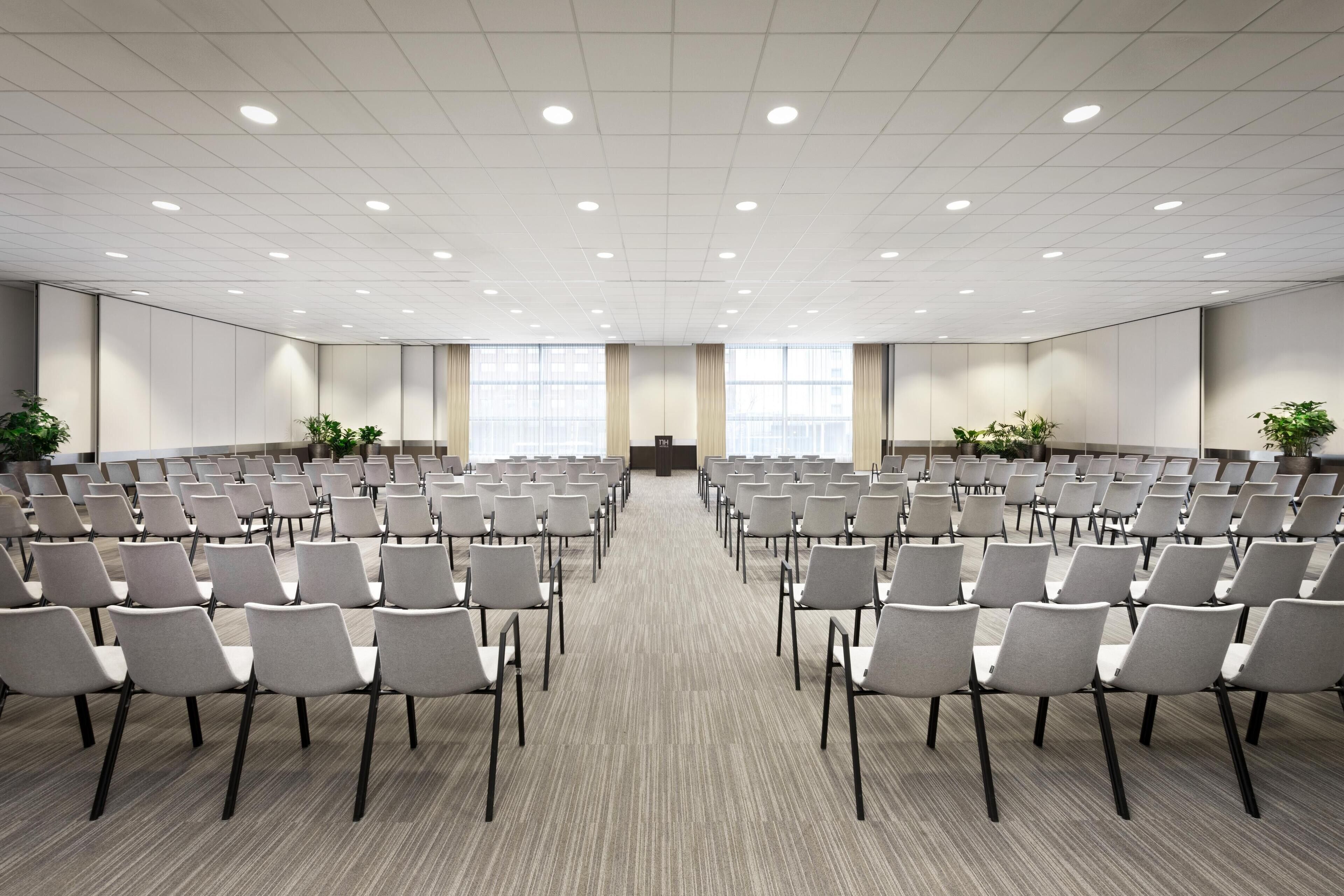 A conference room with rows of chairs, a podium, and large windows.